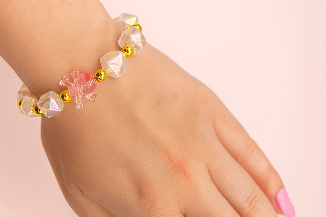 Roze Crystal Skull Charm armband – handgemaakte stretcharmband met iriserende kralen, gouden accenten en roze skull bedel 